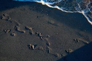 orme nel il sabbia su il spiaggia, sabbioso spiaggia, mare onde. foto