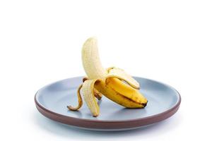 giallo maturo banane posto su un' piatto maturo banane con nero macchie su il sbucciare. Banana troppo maturo marcio, isolato su bianca sfondo foto