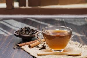 avvicinamento tiro di un' tazza di caldo tè o caffè posto su un' scrivania o un' tavolo, potabile caffè di il finestra a opera o a casa, a tramonto o nel il mattina. foto