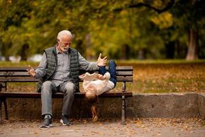 nonno la spesa tempo con il suo nipotina su panchina nel parco su autunno giorno foto