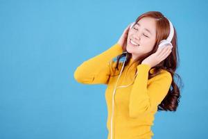 bellissimo donna è godendo ascoltando per musica con cuffie su un' leggero blu sfondo. foto