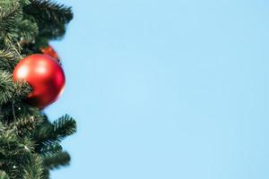 avvicinamento di rosso fronzolo sospeso a partire dal un' decorato Natale albero su sfocato di luci con decorato albero, scintillante e bokeh sfondo. copia spazio per il tuo testo. foto