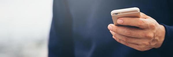 il giovane indossa una camicia a quadri. mano ravvicinata utilizzando il telefono cellulare durante il riposo sul divano. seduto a guardare il messaggio sullo smartphone mobile durante la pausa relax. focalizzazione morbida. foto