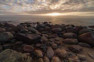 pietre su il costa di il baltico mare a tramonto foto