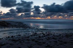 baltico mare costa con ciottoli e ghiaccio a tramonto foto