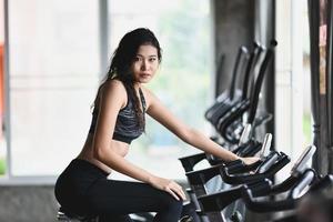 asiatico sportiva esercizio su un' bicicletta nel il palestra, determinazione per cardio perdere il peso, fa sua sano. esercizio bicicletta donna fitness sport concetto. foto