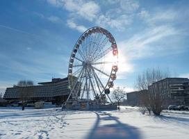 Ferris ruota Cracovia occhio nel il controluce contro un' blu cielo con nuvole su gelido inverno giorno. Hotel nel il sfondo. orizzontale foto. Cracovia, Polonia, Europa. foto