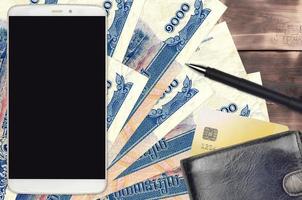 1000 cambogiano riel fatture e smartphone con borsa e credito carta. pagamenti elettronici o e-commerce concetto. in linea shopping e attività commerciale con portatile dispositivi foto