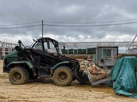 costruzione luogo di un industriale complesso. piccolo case per costruttori con finestre. un' trattore su grande ruote cavalcate nelle vicinanze e trasporti edificio materiale foto