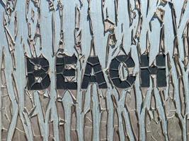 vecchio Cracked iscrizione spiaggia nel grande lettere su il piatto. un' brutale spiaggia vacanza concetto foto