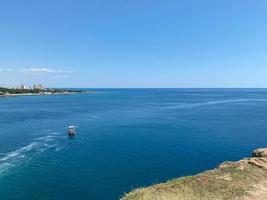 crociera nave rivestimento va in orizzonte il blu mare in partenza un' pennacchio su il superficie di il acqua paesaggio marino durante Alba. aereo Visualizza, concetto di mare viaggiare, crociere foto