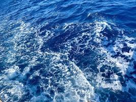 ribollendo ghiaccio onde di il settentrionale oceano. traslucido blu-turchese acqua con mare schiuma retroilluminato di il sole. trasparente. sfondo. modello foto