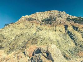 montagna su il mare. alto, sabbioso scogliera con pietre a il ricorrere. roccia per arrampicata e alpinismo. roccia struttura foto