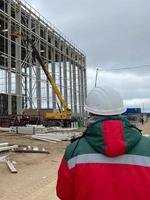 ritratto ingegnere uomo indossare sicurezza casco in piedi indietro e guardare per il costruzione luogo con moderno città sfondo. industria, ingegneria, costruzione concetto. con copia spazio per il tuo testo foto