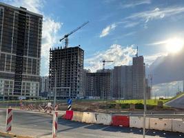 riparazione e costruzione di un' strada con temporaneo strada segni e coni contro il sfondo di bellissimo alto nuovo edifici contro il sfondo di blu cielo e arcobaleno nel un' grande città foto