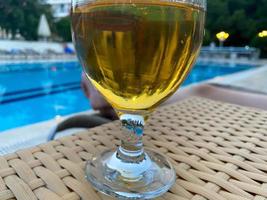 pianura pinta bicchiere di freddo birra chiara birra seduta su bordo di blu nuoto piscina foto