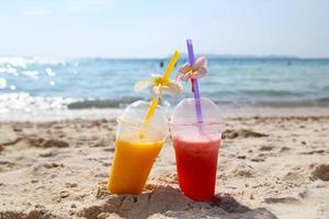 viaggio per isola KOH larn, Tailandia. Due bicchieri con Mango succo e anguria succo su il spiaggia nel il soleggiato estate tempo atmosferico. foto