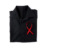 rosso nastro su un' nero camicia su un' bianca sfondo. moderno trattamento e assistenza sanitaria. AIDS consapevolezza concetto. foto