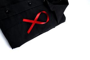 rosso nastro su un' nero camicia su un' bianca sfondo. moderno trattamento e assistenza sanitaria. AIDS consapevolezza concetto. foto