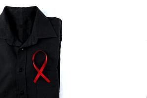 rosso nastro su un' nero camicia su un' bianca sfondo. moderno trattamento e assistenza sanitaria. AIDS consapevolezza concetto. foto