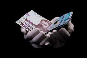 Due mani con grivna. avvicinamento femmina mano dando i soldi per qualcosa con isolato su nero sfondo, conteggio, pagando, shopping con grivna, corruzione, conteggio grivna banconote Ucraina foto