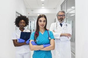 medico professionisti in piedi insieme. concetto di Salute protezione. riuscito squadra di medico medici siamo guardare a telecamera e sorridente mentre in piedi nel ospedale foto