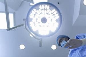 chirurgo in piedi sopra di il paziente prima chirurgia. assistenza sanitaria lavoratore l'esecuzione chirurgia su paziente a operazione Teatro. foto