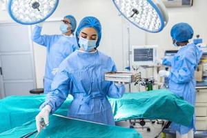 femmina chirurgo nel chirurgico uniforme assunzione chirurgico strumenti a operativo camera. giovane donna medico nel ospedale operazione Teatro