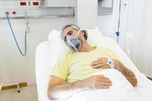 nel il ospedale anziano covid-19 paziente riposa, dire bugie su il letto con ossigeno maschera. ripresa uomo addormentato nel il moderno ospedale reparto. foto