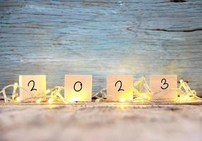 contento nuovo anno 2023 su Marrone legna tavolo e sfocatura astratto bokeh leggero foto