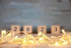 sfocato contento nuovo anno 2023 su legna tavolo e sfocatura astratto bokeh leggero foto