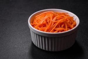 gustoso speziato coreano carota con spezie e erbe aromatiche su un' buio calcestruzzo sfondo foto