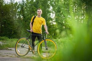 un giovane si è fermato a riposare con la sua bicicletta in un parco pubblico. foto