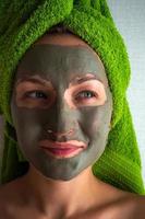 giovane donna con argilla maschera su sua viso contro leggero sfondo, spazio per testo. foto