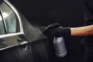 spruzzatura il veicolo. moderno nero automobile ottenere puliti di donna dentro di auto lavare stazione foto