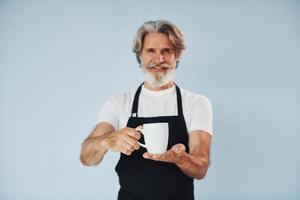 Cameriere con bevande nel mani. anziano elegante moderno uomo con grigio capelli e barba in casa foto