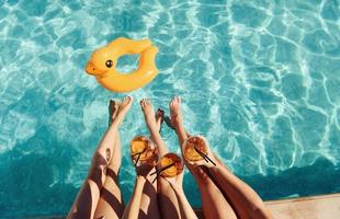 fresco cocktail nel mani. gruppo di giovane contento persone avere divertimento nel nuoto piscina a giorno foto