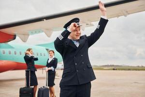 con bagaglio. aereo equipaggio nel opera uniforme è insieme all'aperto vicino aereo foto