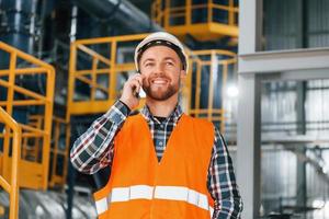 parlando di Telefono. costruzione lavoratore nel uniforme è nel il fabbrica foto