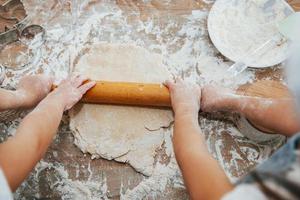 superiore Visualizza di Due poco ragazze mani quello preparazione impastare di attrezzo su il tavolo foto