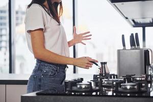 vicino su Visualizza pf giovane bellissimo brunetta nel casuale Abiti quello preparazione caffè nel cucina a giorno foto