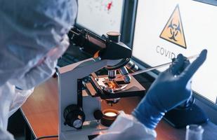 scienziato nel bianca protettivo uniforme lavori con coronavirus e sangue tubi nel laboratorio foto