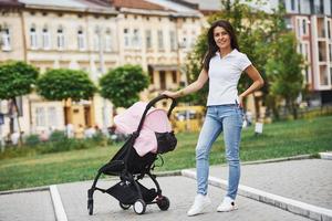 con rosa carrozzina. bella giovane donna avere fine settimana nel il città a giorno foto