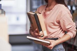 nel casuale Abiti. ragazza ricerca per alcuni informazione nel il biblioteca pieno di libri foto