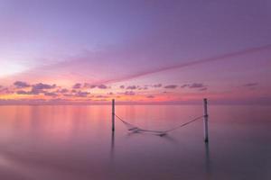 spiaggia a tramonto con al di sopra di acqua amaca, romantico Maldive vacanza. romantico coppia destinazione scenico, cielo mare riflessione. sognare in viaggio foto