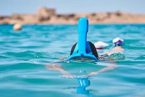 donna con un' boccaglio pieno viso maschera immersione nel blu mare. estate vacanza foto