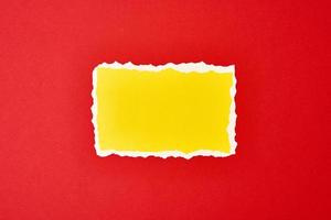 strappato giallo carta strappato bordo foglio su un' rosso sfondo. foto