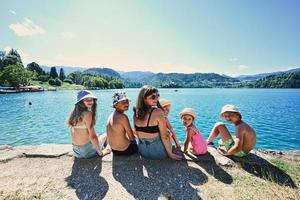 donna con cinque bambini sedersi nel molo di Visualizza bellissimo sanguinato lago, slovenia. madre di molti bambini. foto