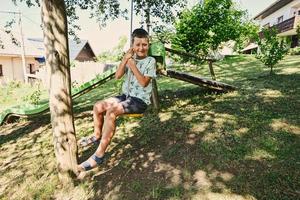 ragazzo oscillante su un' corda contro diapositiva nel montagna villaggio. foto