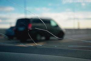 Visualizza attraverso Cracked bicchiere su il strada, pietra fracassato auto parabrezza foto